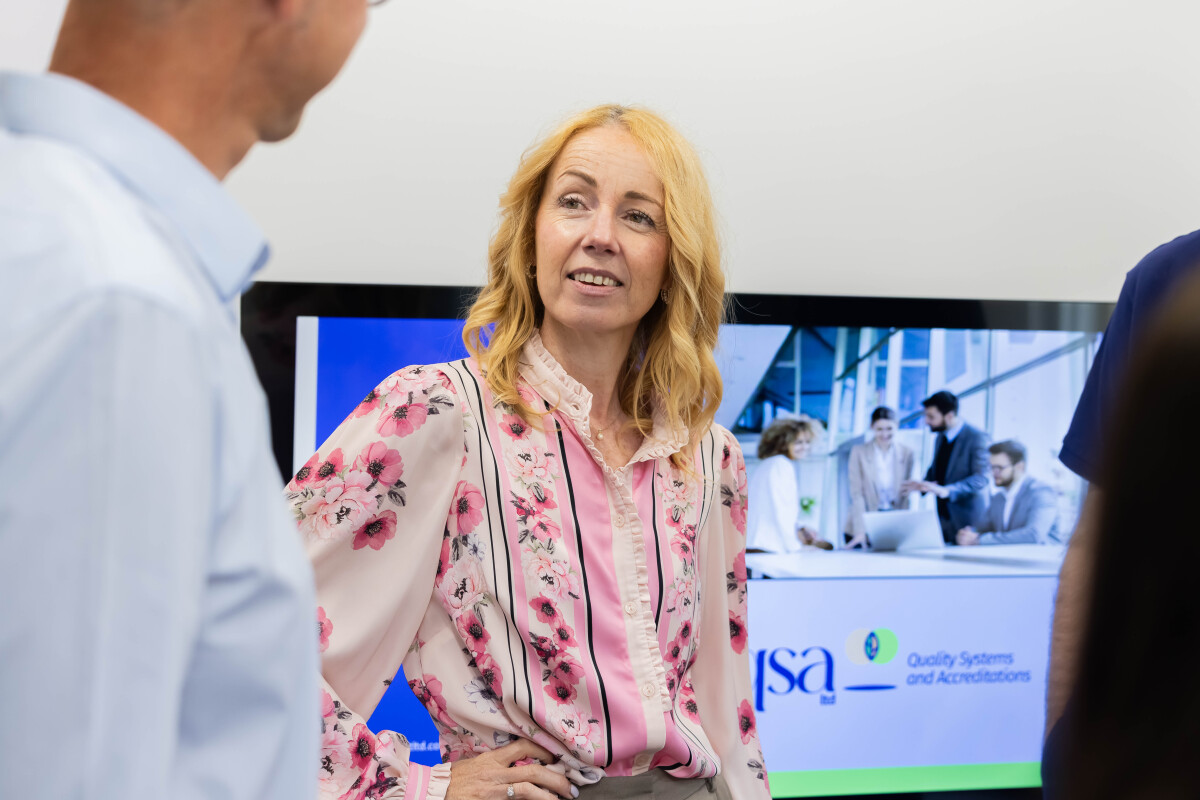 Female Quality Consultant having a conversation with a man in front of a large presentation screen