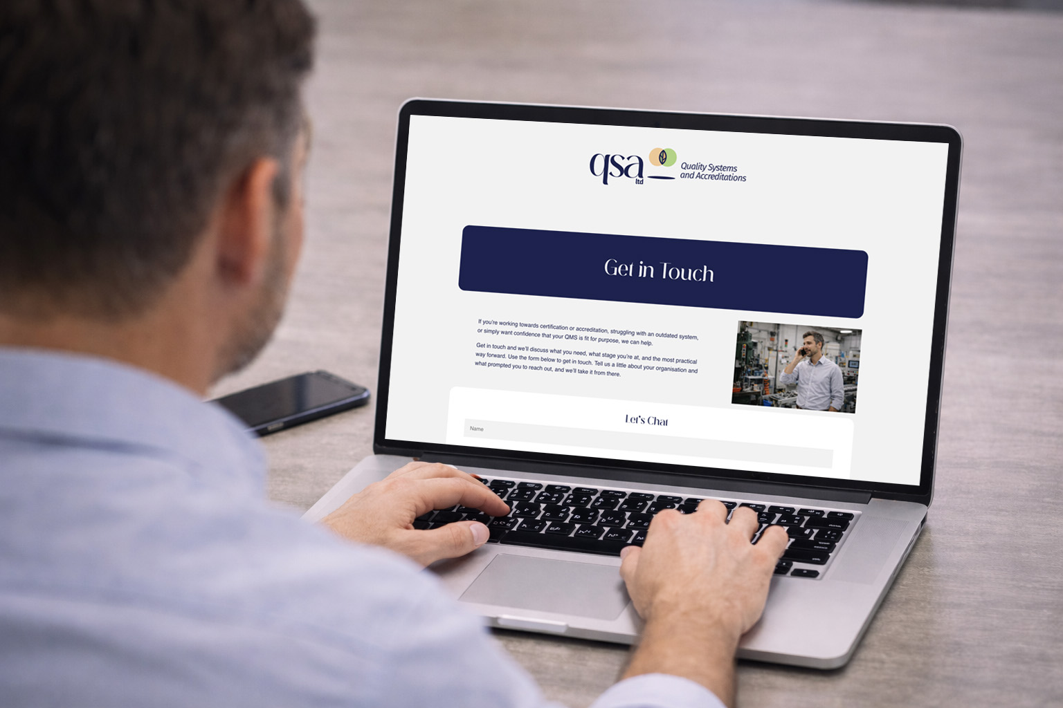Man typing on his laptop on the QSA website contact us page.